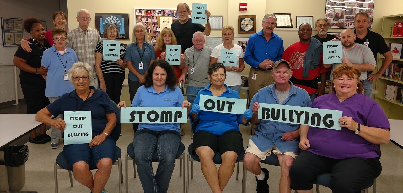 DBS Braille and Talking Book Library staff and volunteers wearing blue and holding up signs that read Stomp Out Bullying.